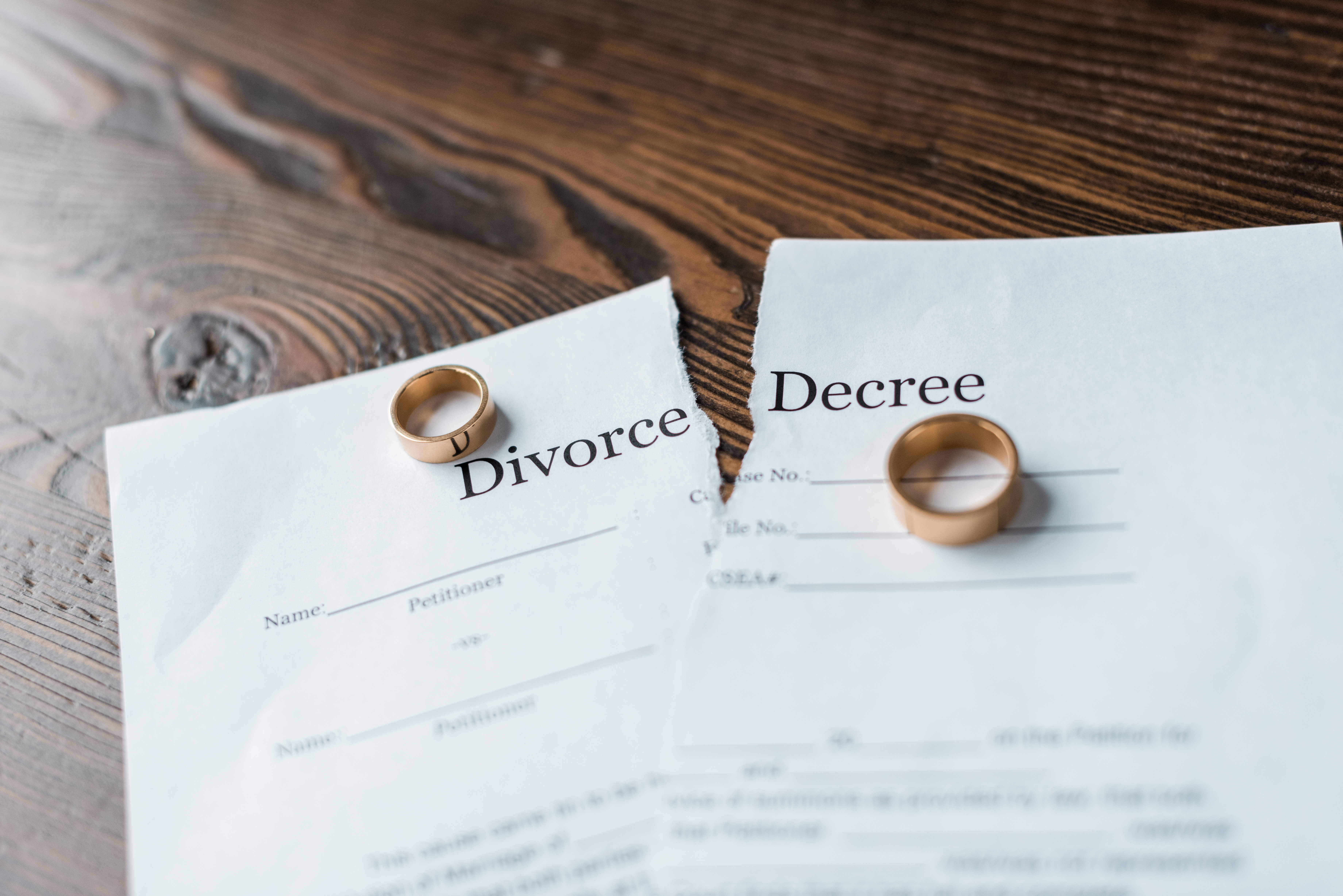 Torn divorce decree with wedding rings on each half, symbolizing the end of a marriage and the divorce process duration