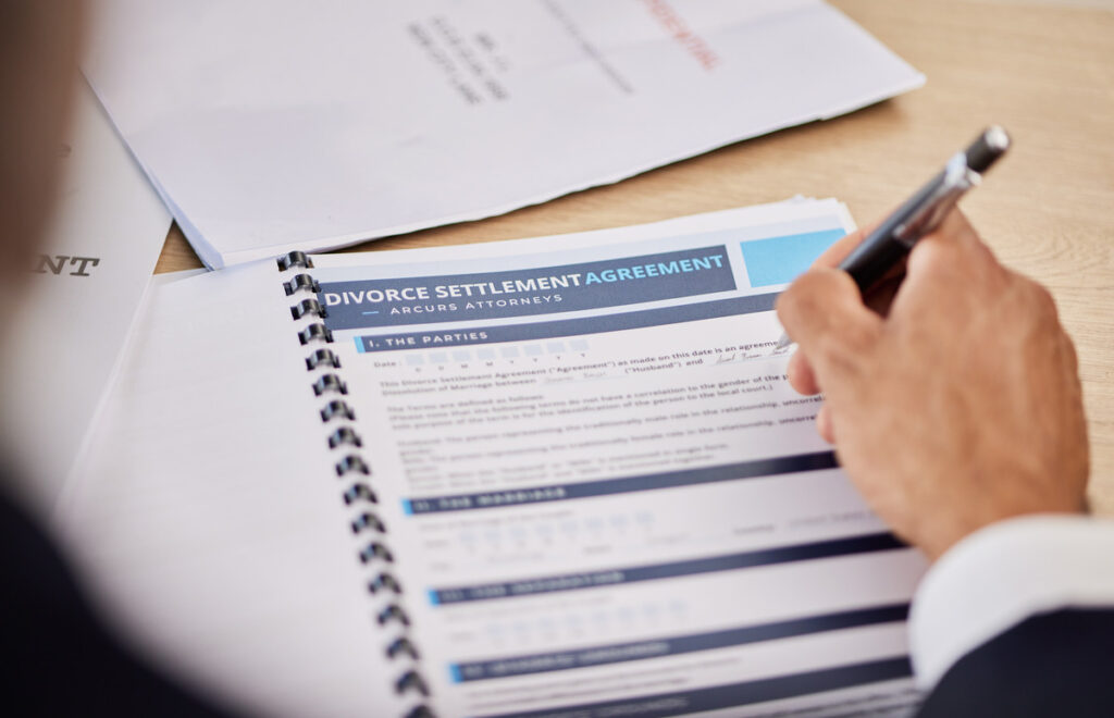 Close-up of a person reviewing a 'Divorce Settlement Agreement' from a law firm, illustrating how long does a divorce take