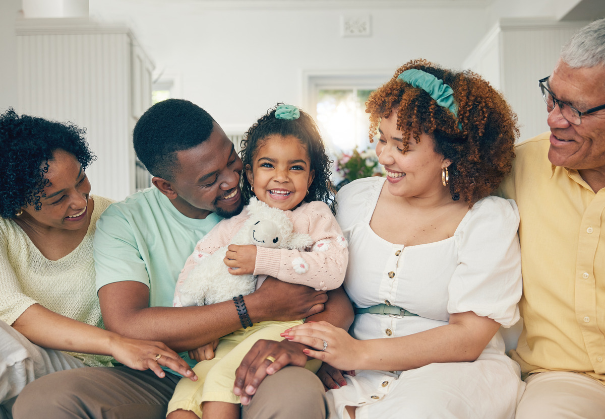 Family sitting closely on a couch, child in the center holding a stuffed animal, symbolizing the complex dynamics of guardianship and parental rights