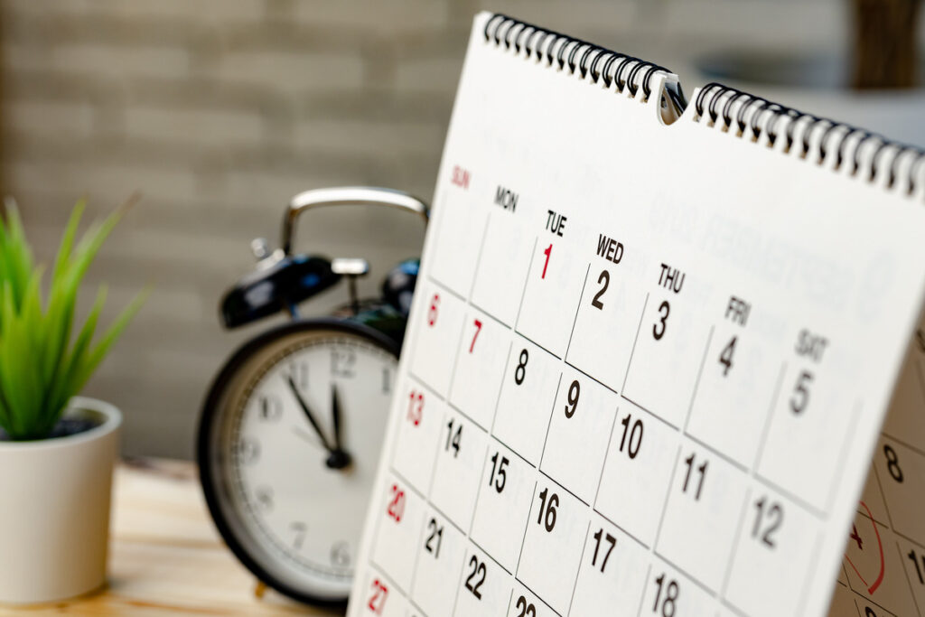 Close-up view of a desk calendar and clock, representing time management in guardianship and parental rights