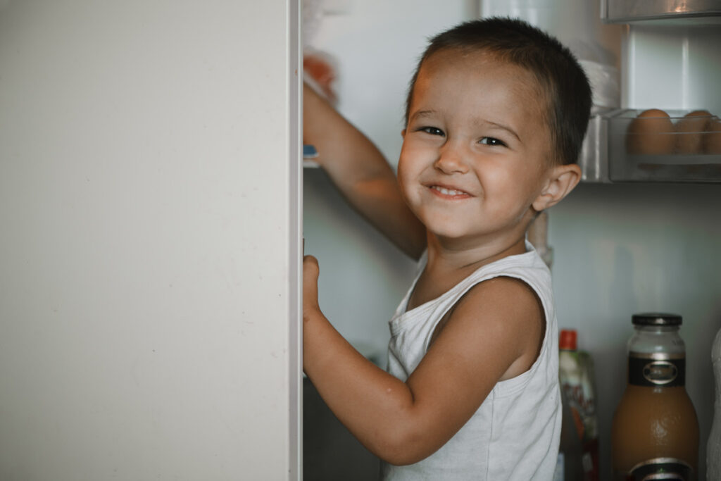 Child reaching into an open refrigerator, symbolizing guardianship responsibilities in daily life and their impact on parental rights