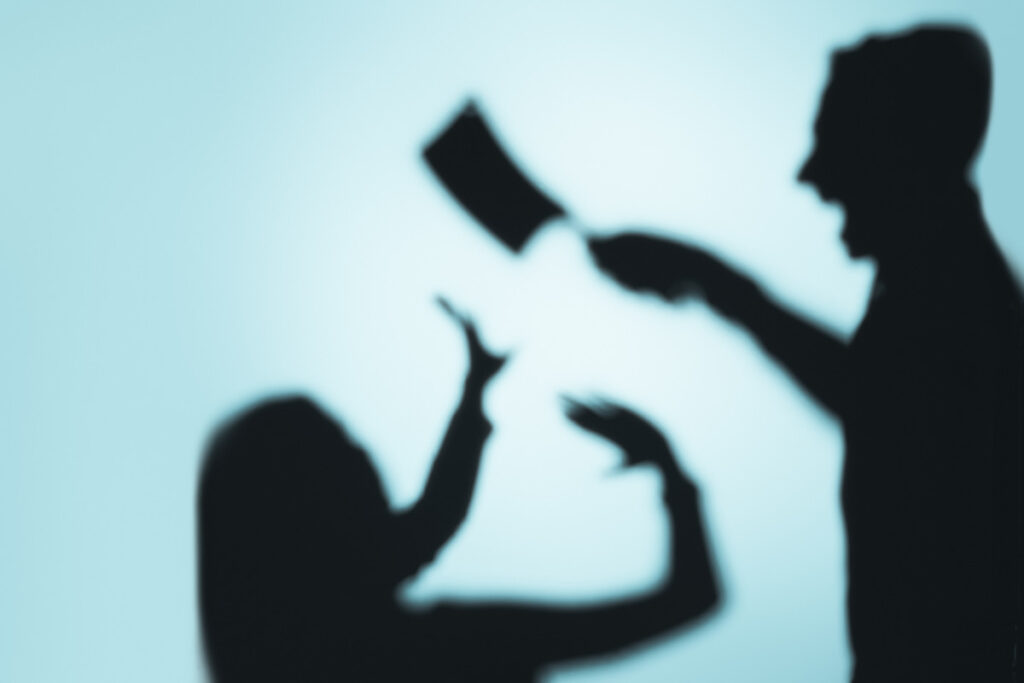 Blurred silhouettes of a person threatening another with a weapon, illustrating the concepts of assault and battery and their differences in legal terms