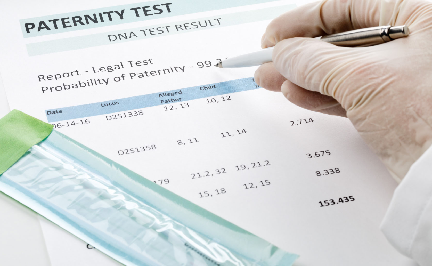 A man's hand holding a pen next to a pregnancy test, symbolizing the contemplation of paternity testing costs