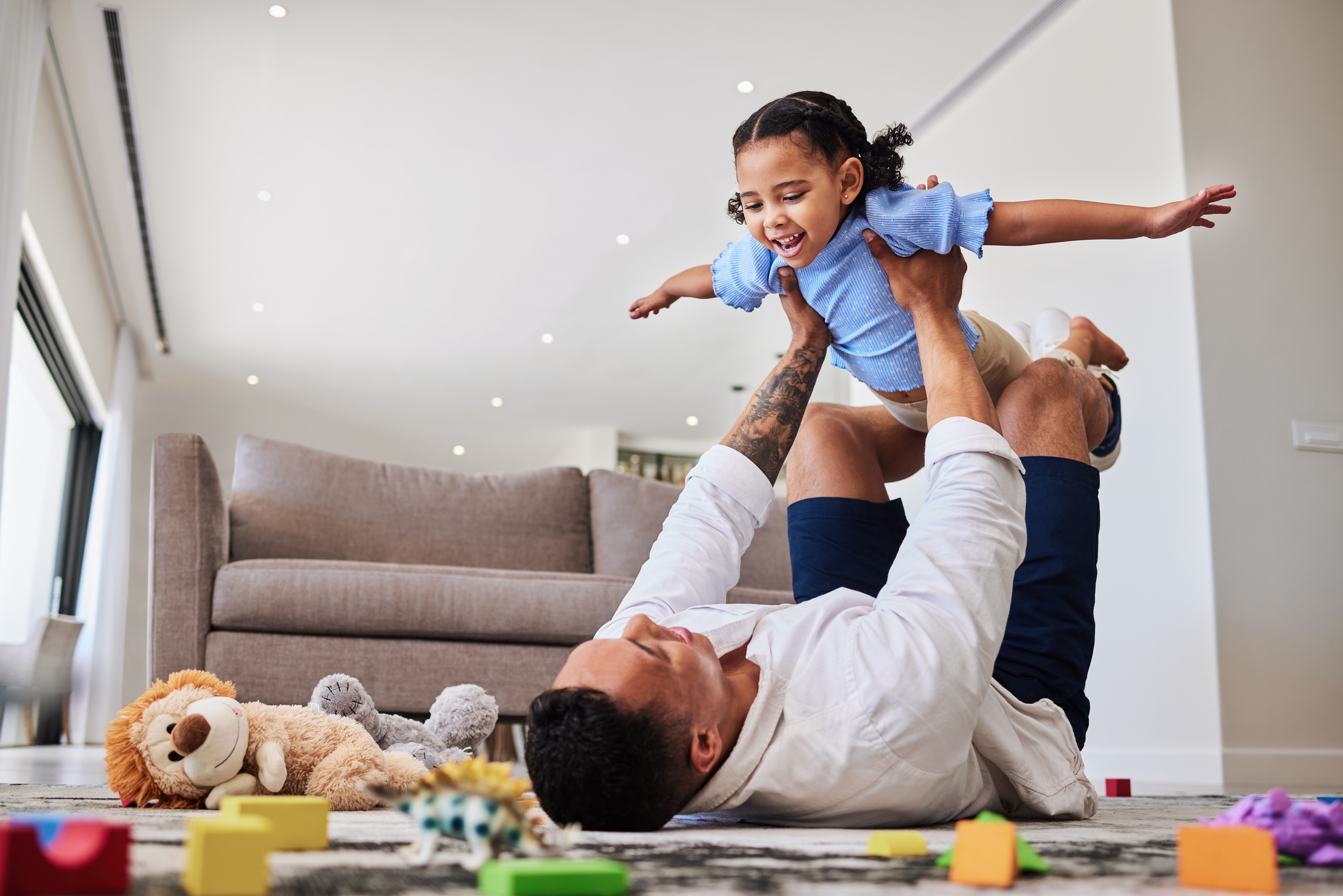 A man and a child joyfully playing together on the floor, showcasing a moment of bonding and happiness