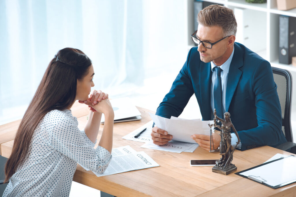A client and lawyer engaged in conversation at a desk, discussing the delay in a car accident settlement process