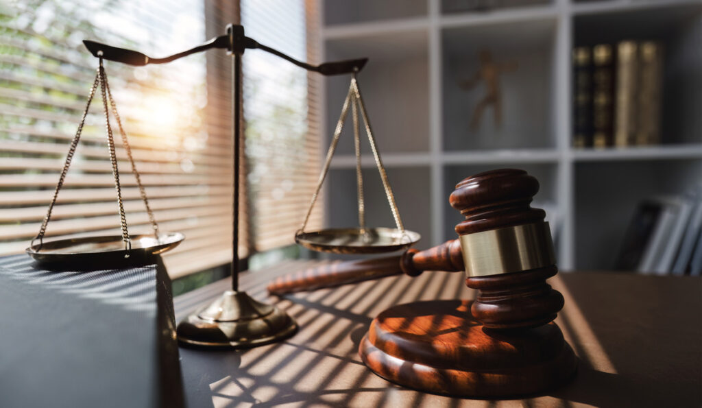 A wooden desk featuring a judge's gavel and scales of justice, representing the legal system and court decisions