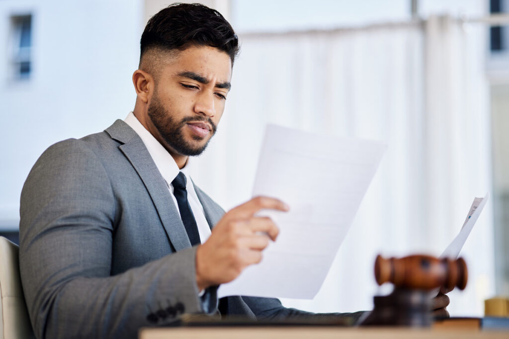 A man in a suit reading a document, possibly related to premises liability and legal responsibilities