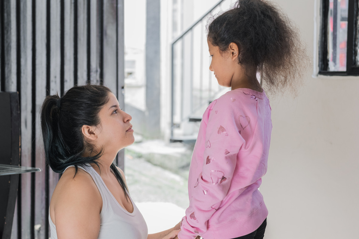 A woman kneels to speak to her child, fostering a moment of connection and understanding between them