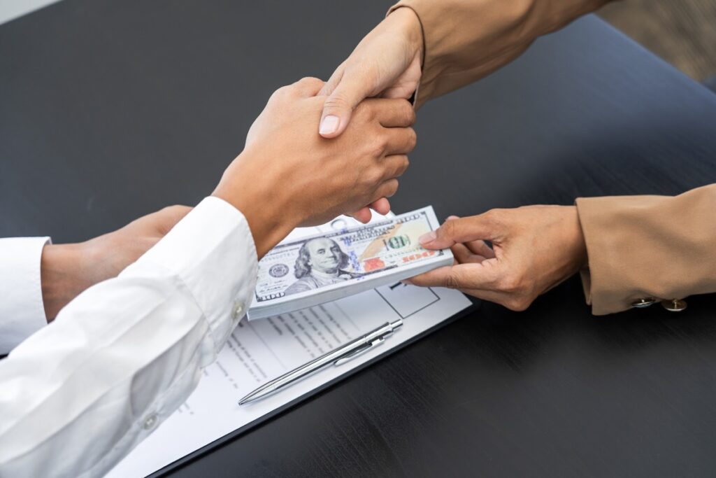 A person giving the other person its lump-sum alimony while shaking hands for agreement