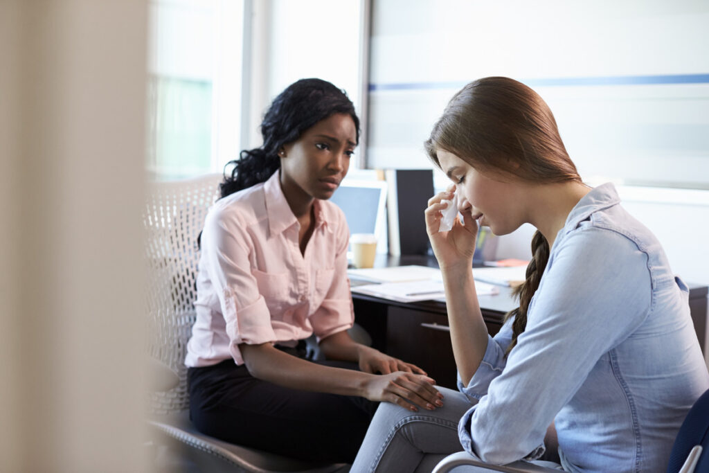 Two women engaged in a serious discussion in an office setting, addressing the topic of termination of parental rights
