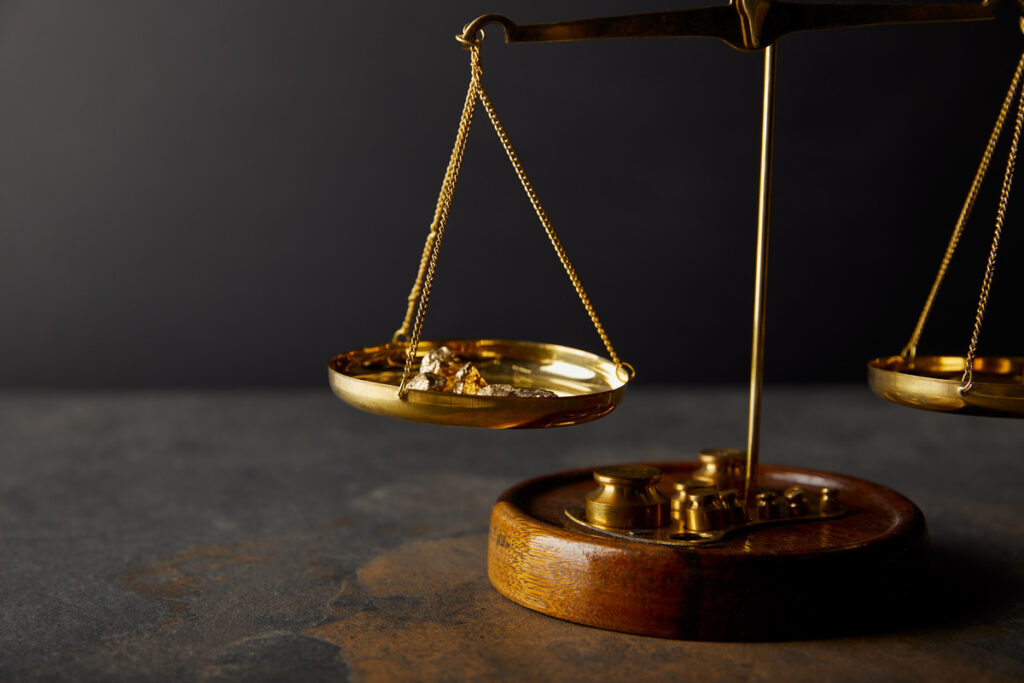 Golden scales with a small figurine on top, symbolizing balance and fairness in collaborative divorce proceedings