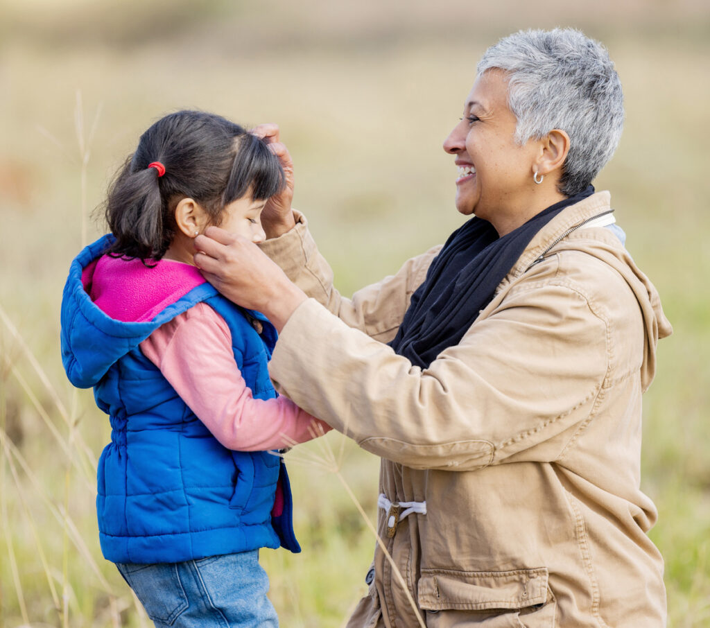 An older woman gently assists a young girl with her hair, symbolizing care and support amidst challenges of parental rights