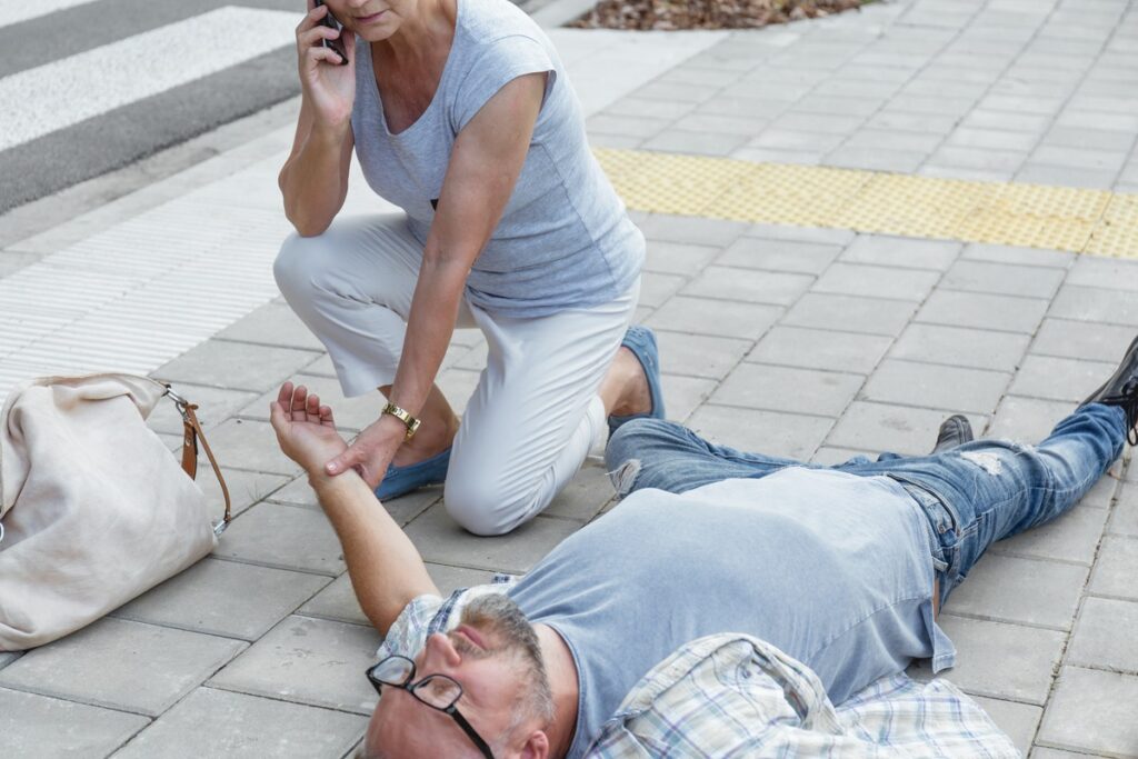 A man on the ground after a slip and fall, while a woman speaks on her cell phone, possibly seeking help or reporting the incident