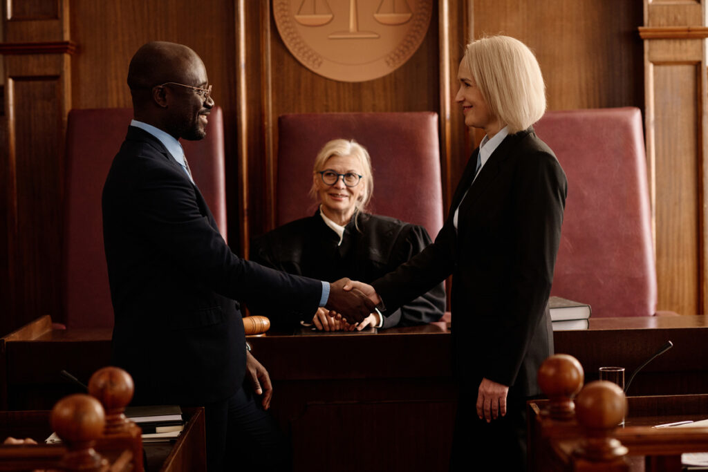 Two individuals shaking hands in a courtroom, symbolizing a collaborative divorce agreement