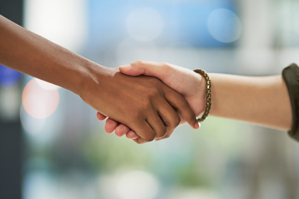 Two individuals shaking hands outside a building, symbolizing a collaborative divorce agreement
