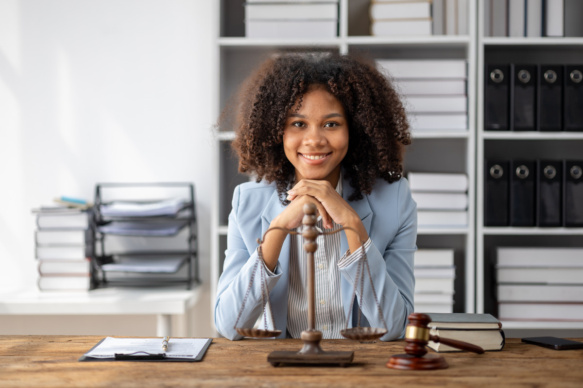 A smiling female lawyer at her desk, with a scale of justice, representing a family law lawyer in Houston