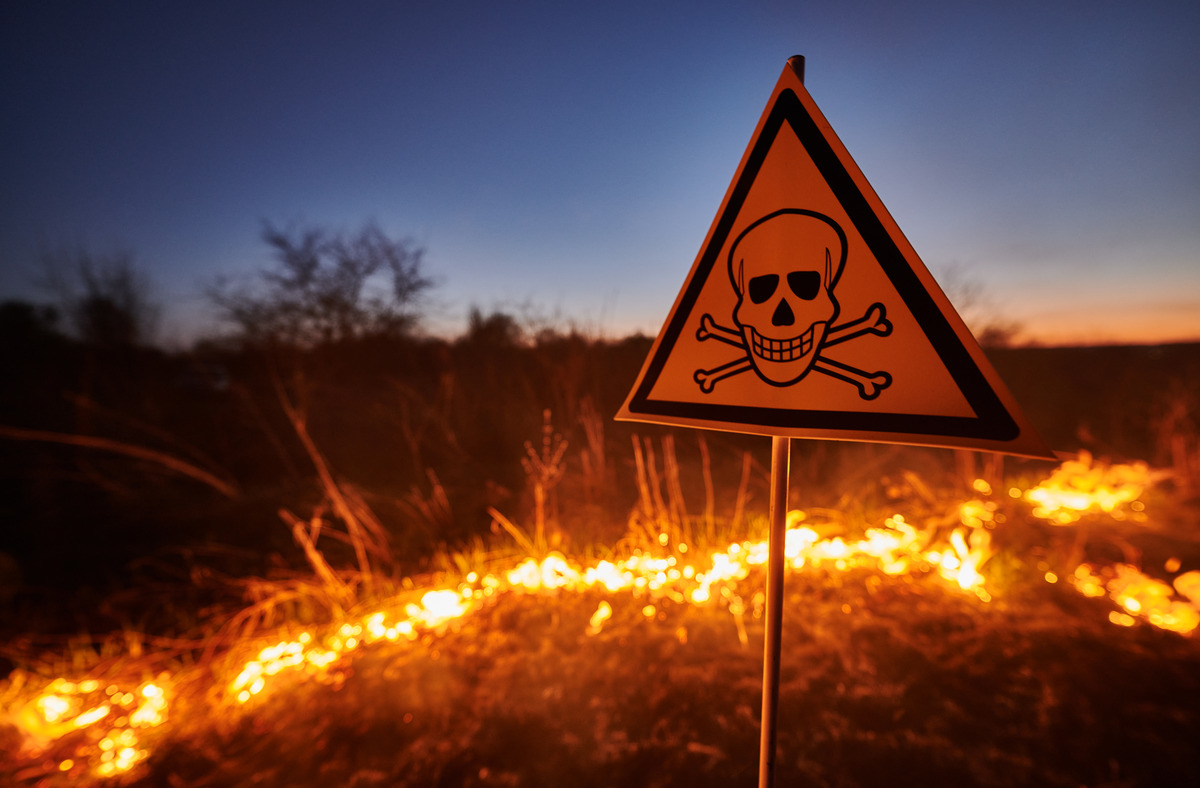 A "danger" sign stands in front of a fire, warning of potential hazards associated with flames