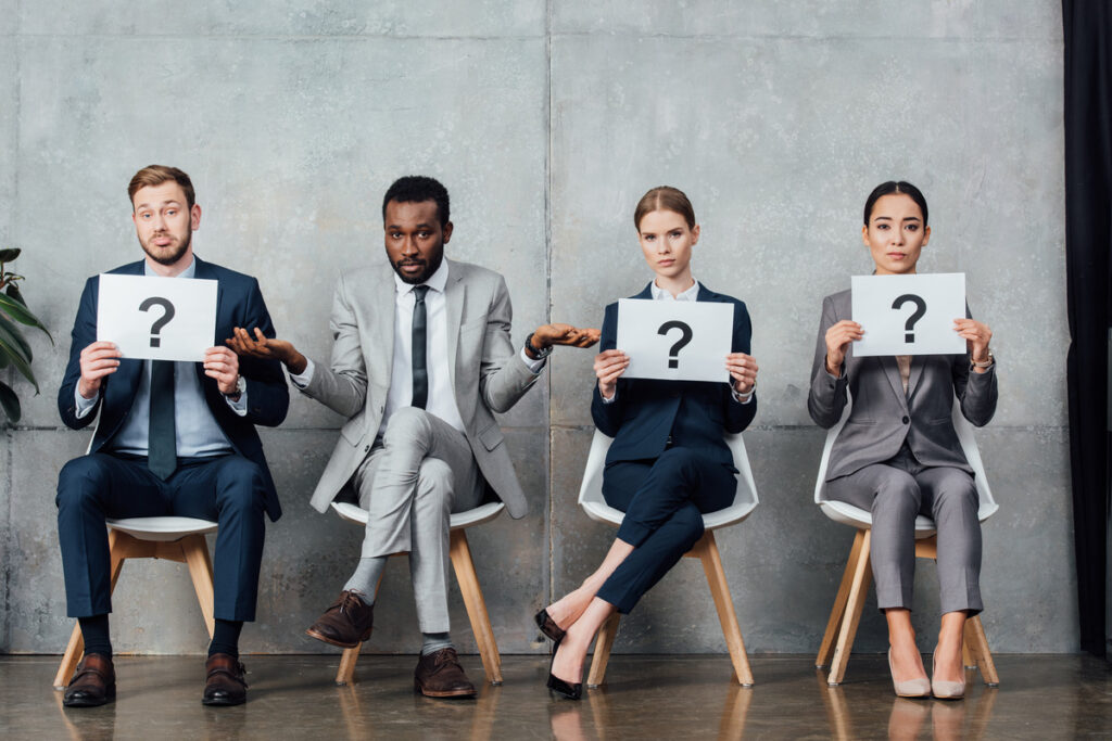 Business professionals seated, each holding question signs, symbolizing inquiries related to family law in Houston