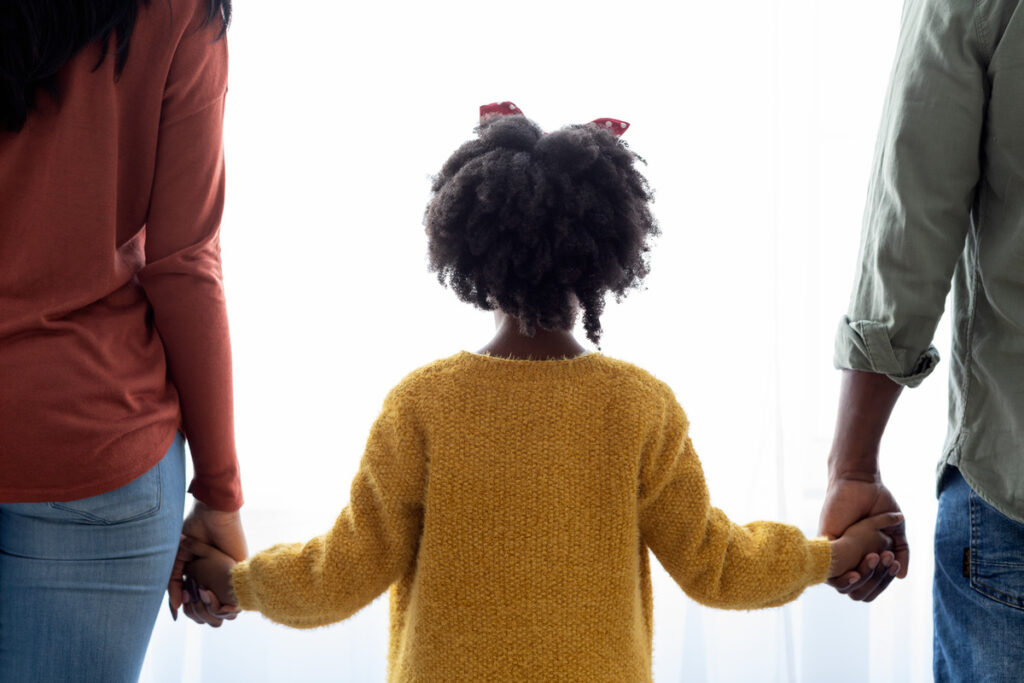 A family united, holding hands in front of a window, symbolizing support during the divorce process in Texas