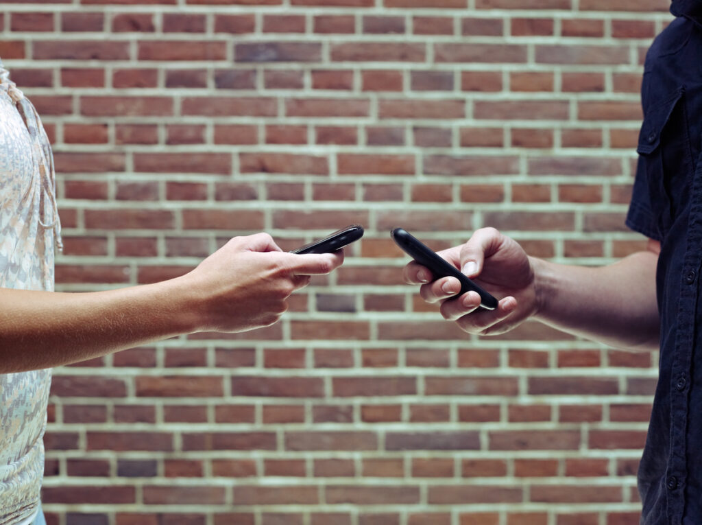 Two individuals engaged in a discussion, each holding a cell phone, reflecting on the divorce process in Texas