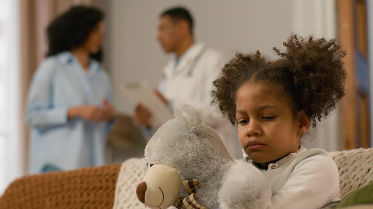 a sad child while parents discussing on the background about co-parenting
