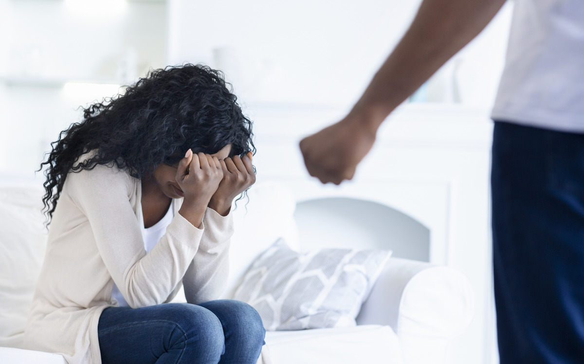woman hiding her face from her angry husband