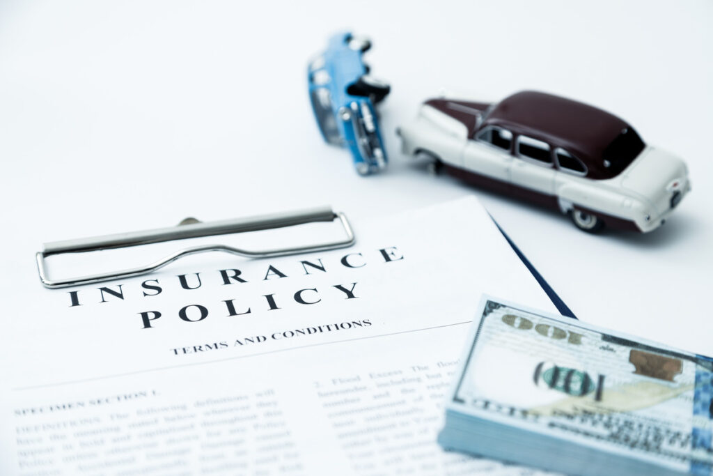 Insurance policy document with a miniature car and stack of money