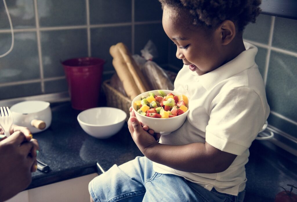 A kid holding a bowl of fruits