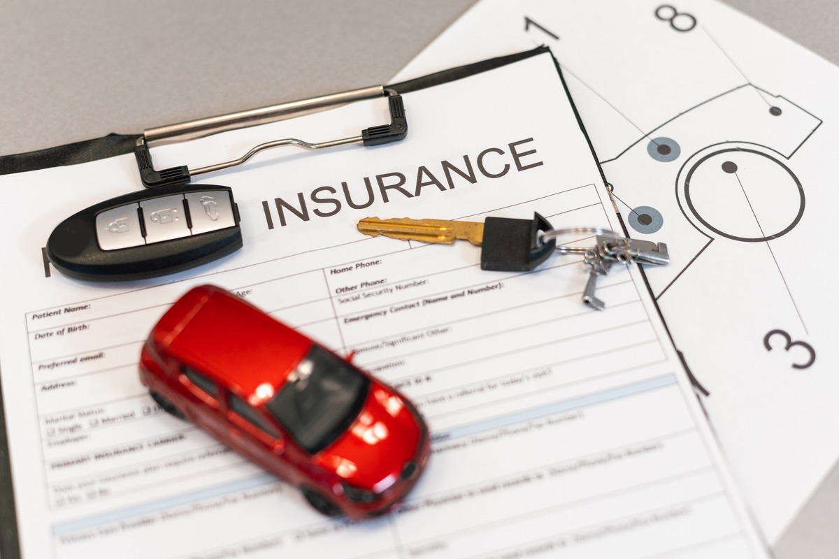 Insurance policy document with a toy car and a key of a vehicle on top