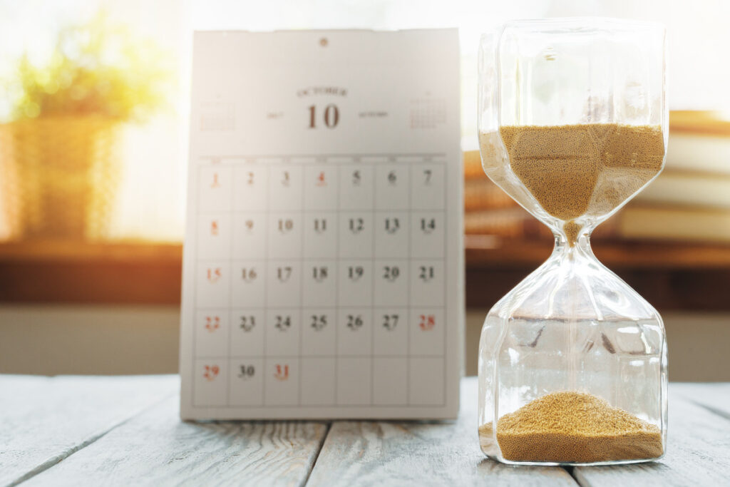 an hourglass with a calendar on the background
