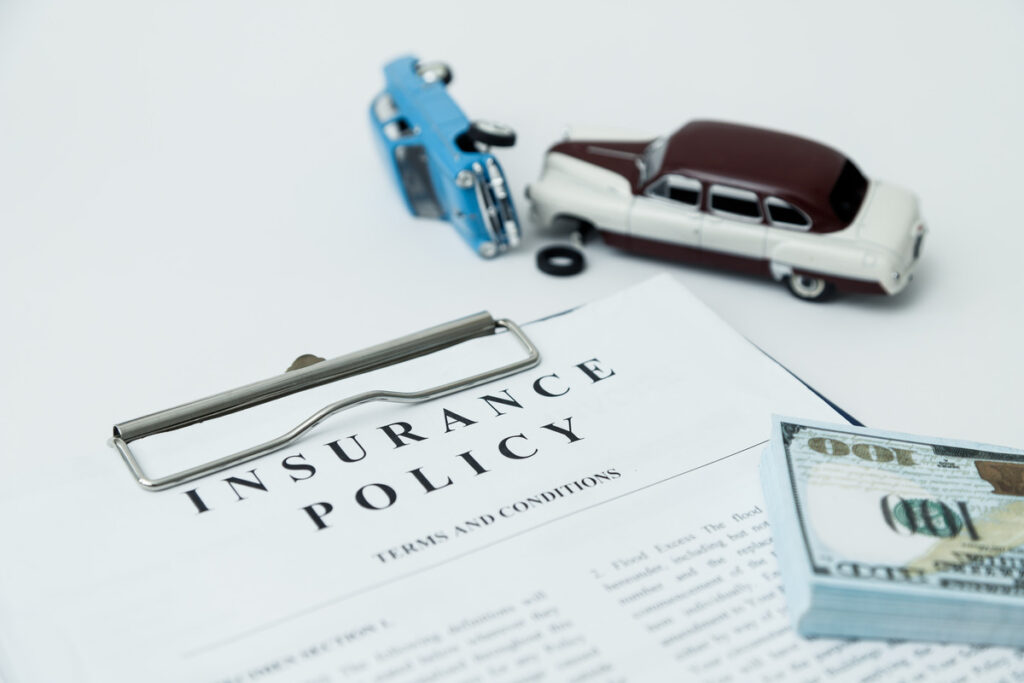 two toy cars modeling a car accident with an insurance policy document