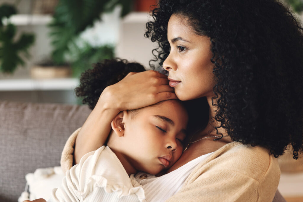 a mother hugging her sleeping daughter