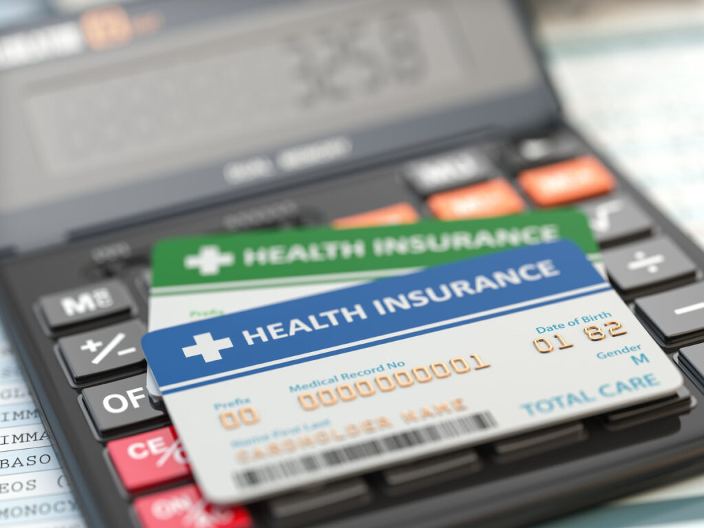 Health insurance cards on a calculator