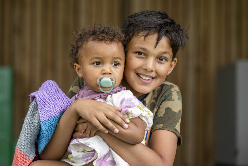 a boy smiles while embracing his sibling